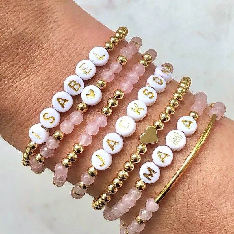 Bracelets de perles au prénom empilés au poignet, perles roses et dorées
